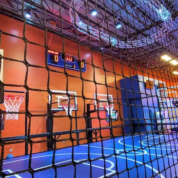 Indoor sports court with basketball hoops, scoreboard, and vibrant blue flooring, designed for children's activities and birthday parties at GAME LAB.